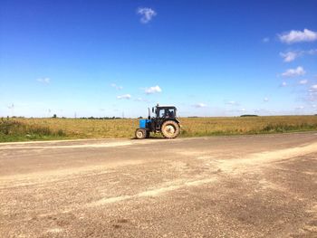 Tractor on road against blue sky