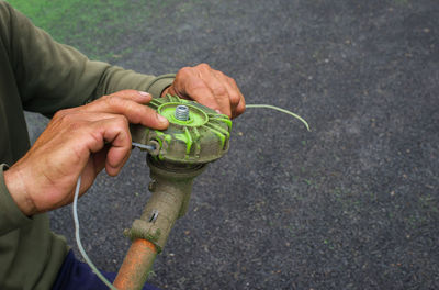 Midsection of worker repairing mower on footpath