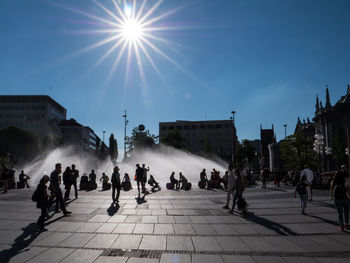 People on street in city against bright sun