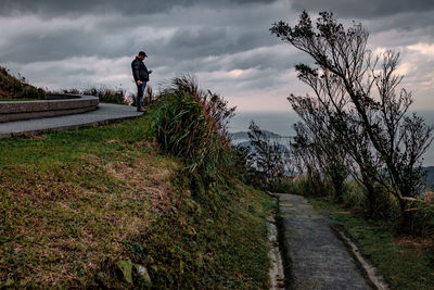 Man smoking on footpath against sky