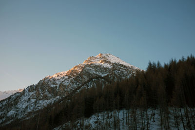 Low angle view of snowcapped mountains against clear sky