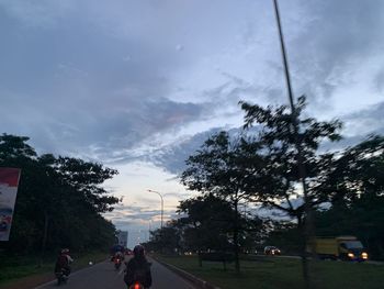 People walking on road in city against sky