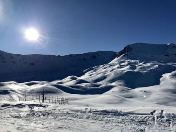 Scenic view of snow covered mountains against bright sun