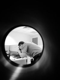 Side view of man photographing seen through window