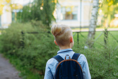 Caucasian boy walking to school wearing school bag. begining of academic year