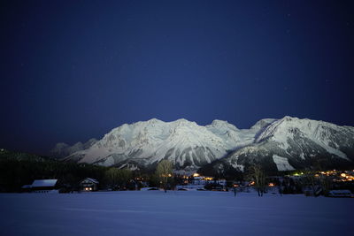 Scenic view of snowcapped mountains against clear blue sky at night