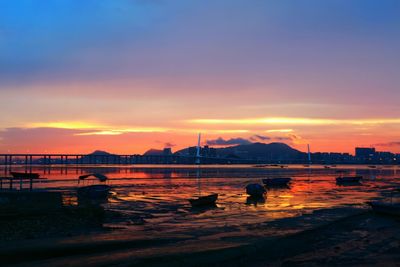 Boats moored in river against cloudy sky during sunset