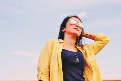 Low angle view of young woman standing against sky