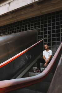 Man sitting on escalator in city