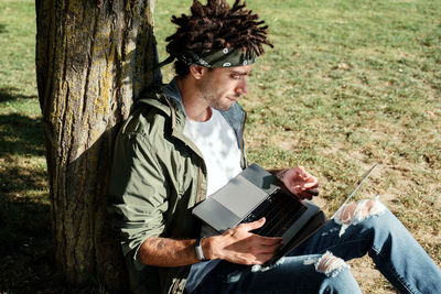 Young man looking at tree trunk