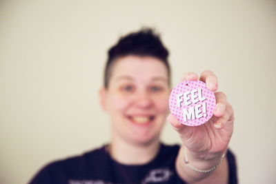 Smiling woman holding badge with text