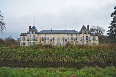 Houses by plants on field against sky