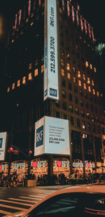 Information sign on road by buildings at night