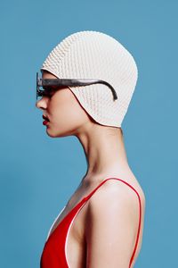 Young woman wearing hat against blue background