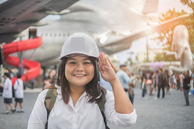 Portrait of smiling young woman saluting wearing hardhat