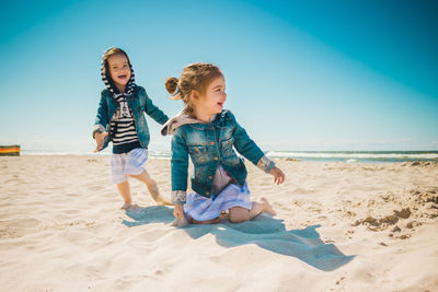 Full length of siblings playing at beach