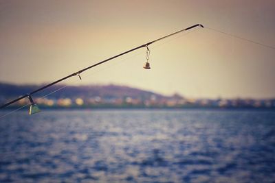 Fishing rod over river against sky