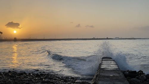 Pier over sea against sky during sunset