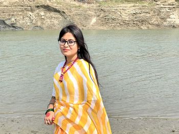 Portrait of young woman standing at beach