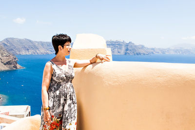 Young woman standing by sea against sky