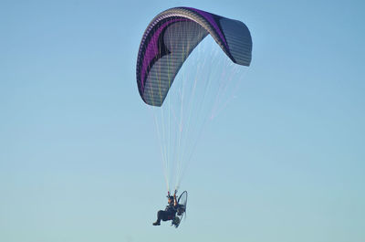 Low angle view of man paragliding against clear sky