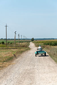 Cars on road amidst field against clear sky
