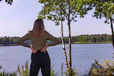 Rear view of woman standing by lake