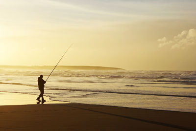 Rear view of man fishing on beach