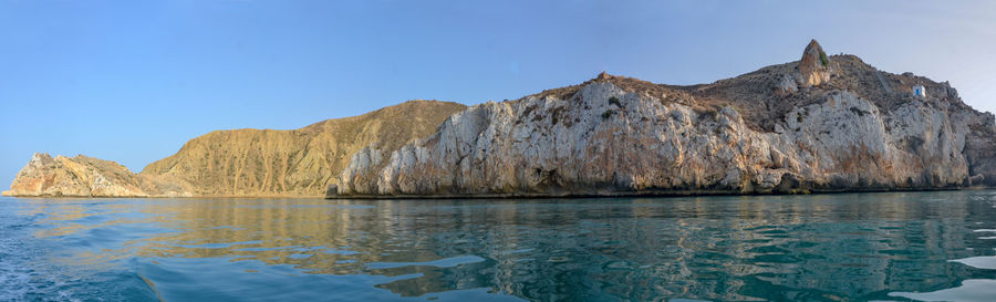 Panoramic view of sea and mountains against clear blue sky
