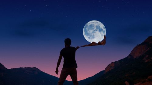 Full length of man standing against moon at night