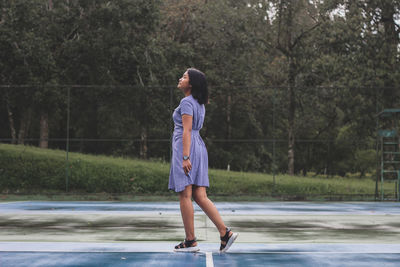 Full length of woman standing on road against trees