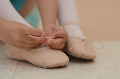 Cropped image of girl tying ballet shoe