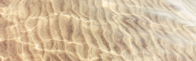 Closeup of sea ocean sand ground with waves ripples. clear clean shallow water on sandy beach 