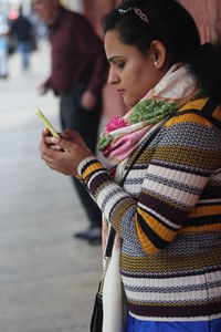 Woman using mobile phone against wall