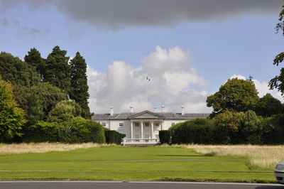 Houses and trees on field against sky