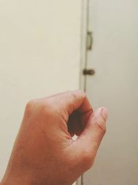 Close-up of human hand against white wall