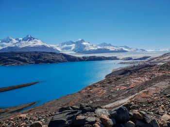 Scenic view of lake and mountains against clear blue sky