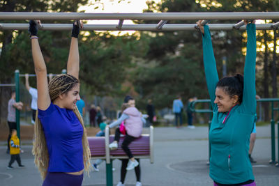 Mother and daughter are working out at the outside gym and having healthy and active lifestyle