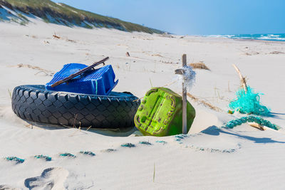 Close-up of umbrellas on sand at beach against blue sky