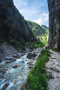 Stream flowing through rocks against sky