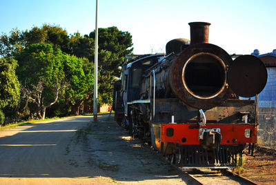 Rusted coal train on railroad track against sky