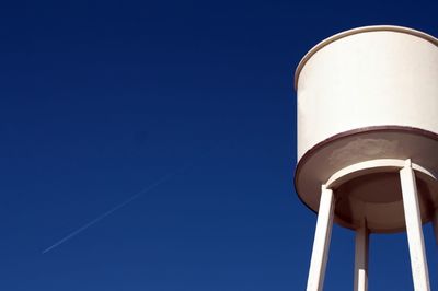 Low angle view of water tower against clear blue sky