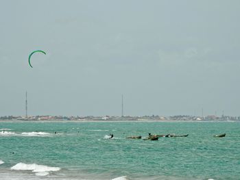 Kite surfer over sea against clear sky