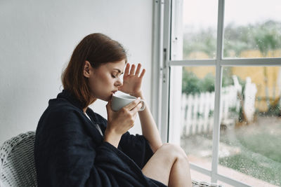 Young woman drinking coffee from glass window