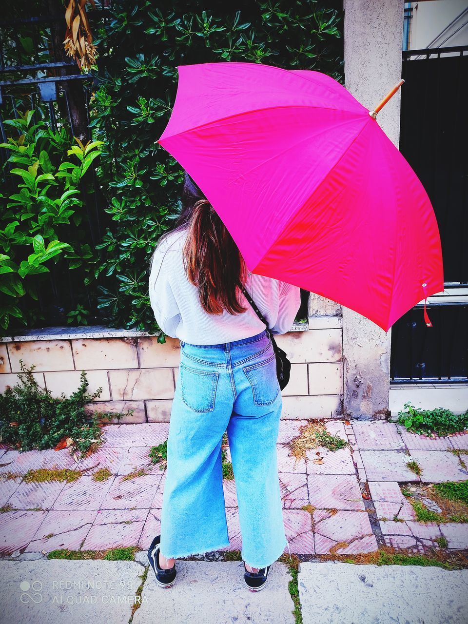 PERSON HOLDING UMBRELLA STANDING ON FOOTPATH