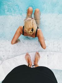 Low section of man standing by woman at poolside