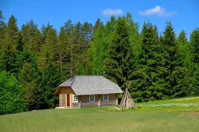 House amidst trees on field against sky