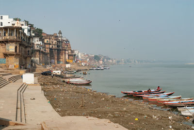 Boats moored on sea by buildings against clear sky