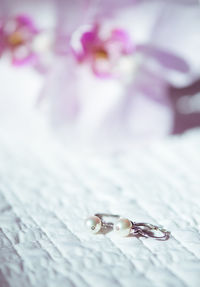 Close-up of pearl earring on bed at home