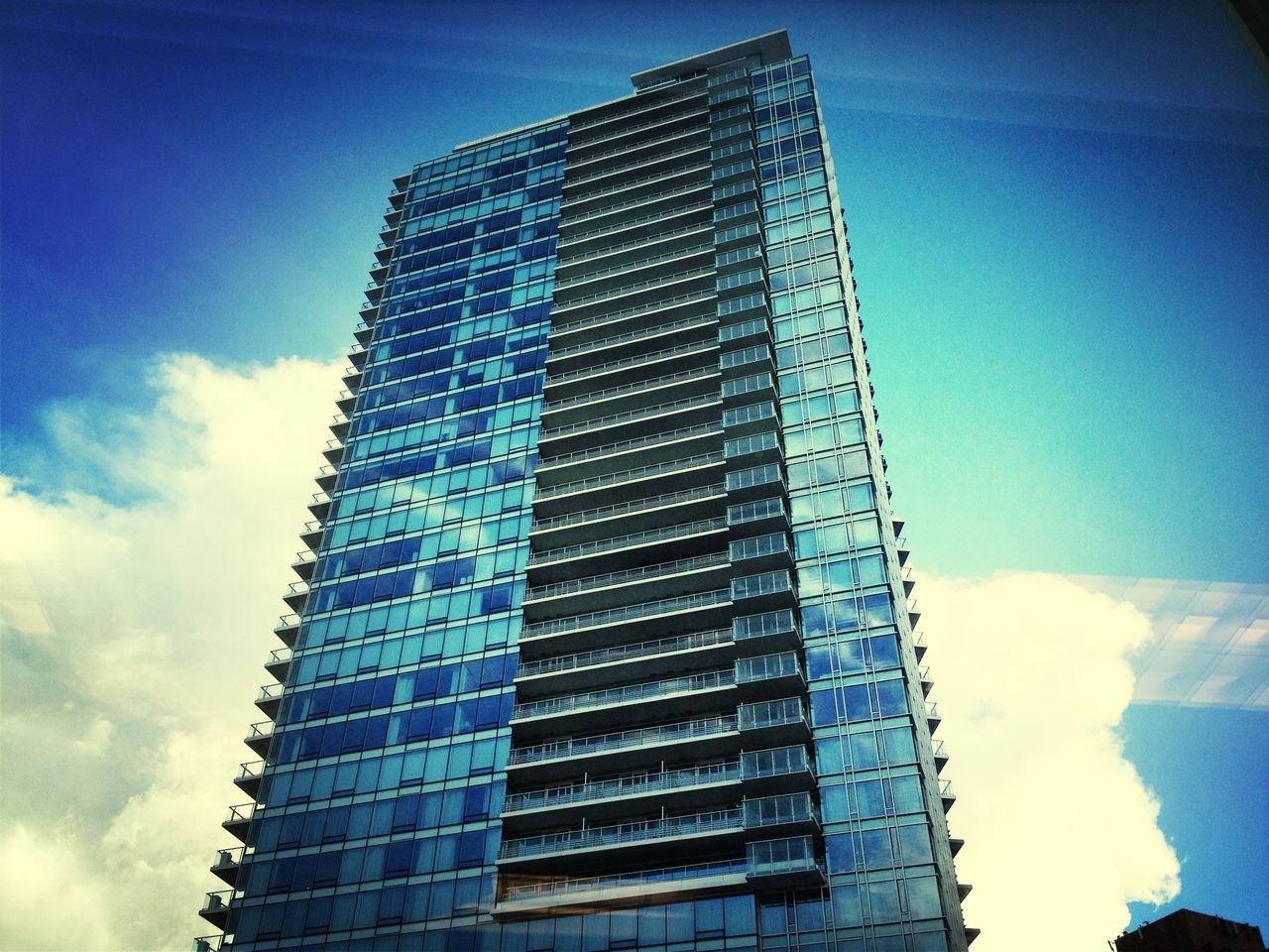 low angle view, building exterior, architecture, built structure, modern, sky, tall - high, skyscraper, office building, tower, city, blue, building, tall, cloud - sky, cloud, day, outdoors, sunlight, glass - material